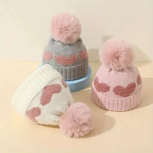 Cozy winter baby knitted beanie with cute heart pattern and fluffy pom-pom, main product view.