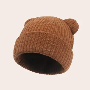 Close-up detail of brown knitted baby hat with cute bear ears and elastic ribbed texture.