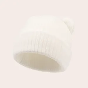 Detailed close-up of a white baby knit beanie hat with cute bear ears and elastic ribbing.