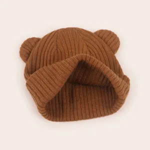 Close-up detail of the brown knit bear ear hat, showing soft ribbed texture and cute design.
