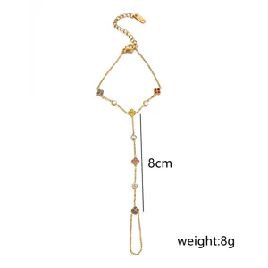 Bracciale da dito dorato con trifogli in zircone colorati, dettaglio catena elegante.