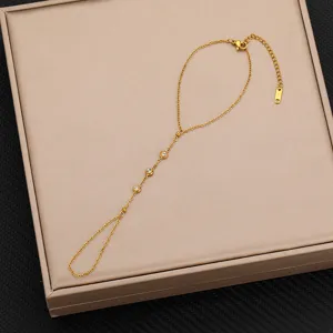 Dettaglio bracciale da dito in acciaio al titanio dorato, elegante gioiello mano zircone.