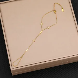 Dettaglio di una catena da mano in acciaio al titanio dorato con ciondoli a stella in zircone delicati.