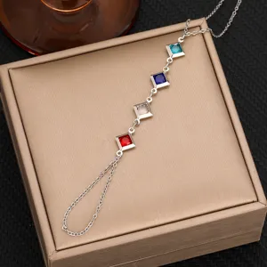 Vista detallada de una elegante cadena de mano plateada con circonitas cuadradas de colores.