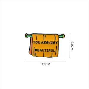 Enamel pin detail showing unique towel design with English text and dimension markings.