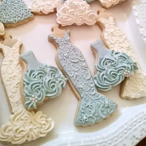Detailed close-up view of elegantly decorated evening dress shaped cookies arranged on tray.