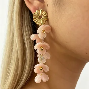 Close-up of long dangling pink resin flower earrings with gold metal stud for women detail.