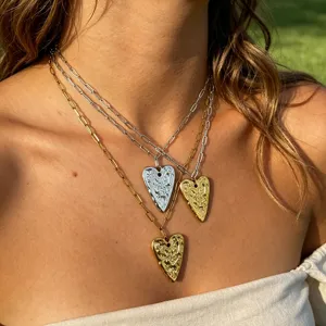 Layered textured heart pendant necklace detail shot, elegant silver and gold chain jewelry.
