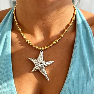 Close-up detailed view of the irregular silver star pendant and gold beaded necklace.