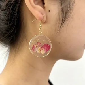 Elegant resin dried flower drop earrings with gold rim, stylish handcrafted jewelry for women.