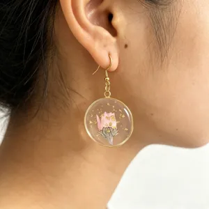 Close-up detail of round epoxy resin dried flower pendant earrings with gold flakes.