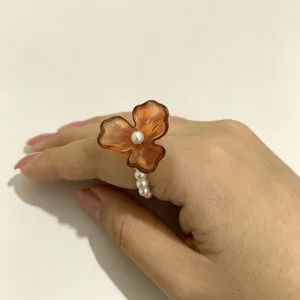 Koreaanse stijl amberkleurige hars driebloemige parel elastische ring close-up detailweergave