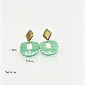 Close-up detail of vintage geometric resin earrings in green and gold, showing size and weight.