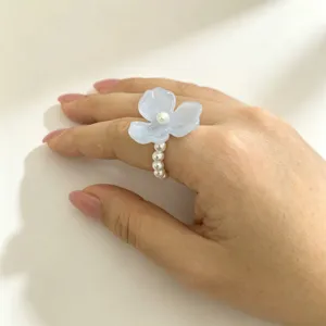 Close-up detailweergave van de elegante blauwe hars bloemring met delicate parelband ontwerp.