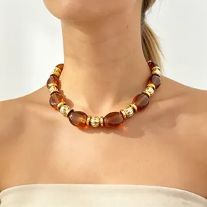 Close-up detail shot of the resin and gold bead statement necklace worn on the neck.