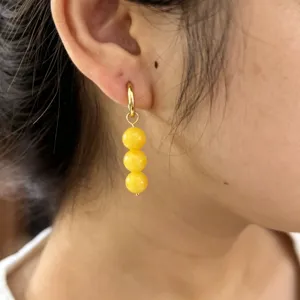 Close-up detail view of the elegant yellow stone three-bead drop earring worn on ear.