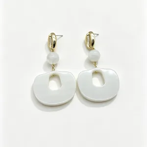 Gros plan de belles boucles d'oreilles géométriques en résine avec coquillage rétro et perle.