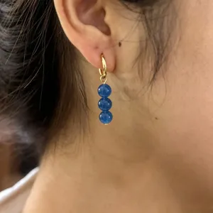Close-up of gold-plated hoop earrings with three blue natural stone round bead drops.
