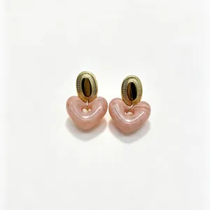 Close-up detail of the pink marbled resin heart pendant paired with textured gold oval stud.