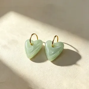 Detail van uitneembare groene hars hart oorbellen met roestvrijstalen gouden creolen.
