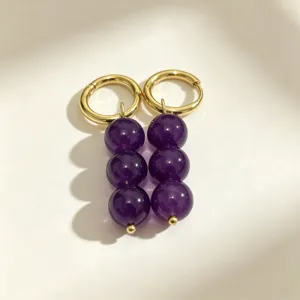 Detailed shot of gold-plated hoop earrings featuring triple purple bead dangles for women.