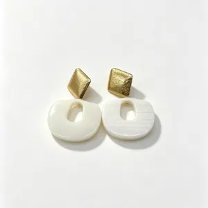 Detailed view of fashionable geometric resin earrings with gold studs and white oval pendants.