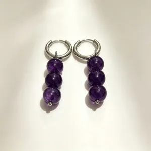 Detailed shot of purple crystal bead hoop earrings, featuring unique dangling design.