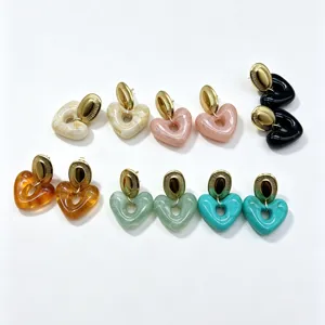 Closeup shot of colorful resin heart earrings featuring gold stainless steel ear stud details.