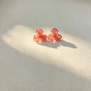 Detailed view of fashionable resin flower stud earrings with sweet pink petals and gold center bead.