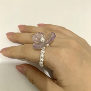 Detailopname van de paarse hars bloem en parel kralen stretch ring op de hand.