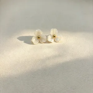 White resin flower stud earrings with a gold tone center bead, sweet floral jewelry detail.