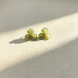 Close-up detail of green resin flower stud earrings featuring a chic gold tone bead center.