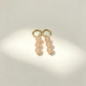 Chic gold hoop earrings featuring elegant dangling peach natural stone round beads detail view.