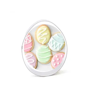 Stainless steel egg cookie cutter with pastel decorated cookie background card for baking.