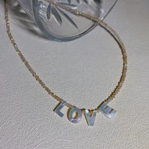 Vista detallada del colgante collar de cuentas LOVE con letras de concha, joya delicada.