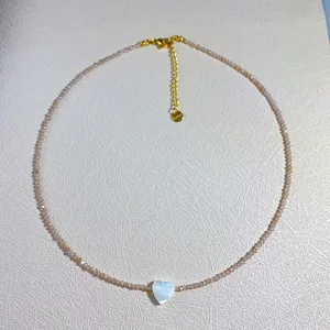 Vista detallada de collar de cuentas con colgante de corazón de nácar y cadena ajustable.
