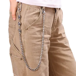 Detail shot of a men's heavy metal punk pants chain featuring skull charms worn on khaki pants.
