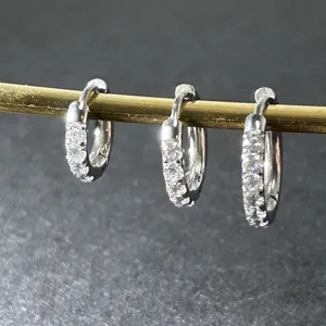 Gros plan détaillé de boucles d'oreilles créoles en acier inoxydable avec des oxydes de zirconium.