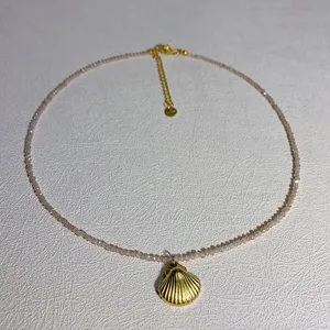 Λεπτό κολιέ choker με ροζ χάντρες κρυστάλλου και χρυσό μενταγιόν κοχύλι λεπτομέρεια.