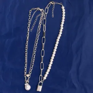 Close-up detail of vintage multi-layer metal chain necklace set with baroque pearl and lock.