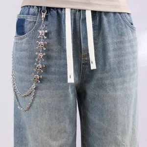 Nahaufnahme von Vintage Destroyed Jeans mit coolem Metall Totenkopf Ketten Accessoire.