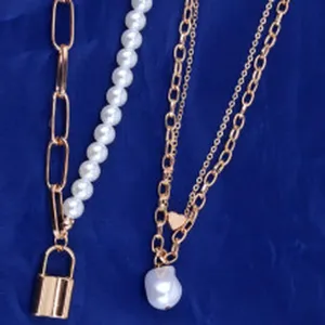 Close-up detail shot of vintage multi-layer necklace set with pearls, lock and heart pendants.