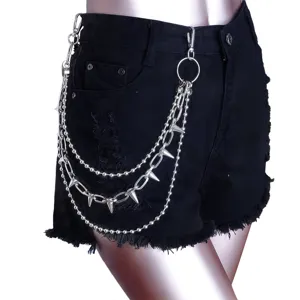 Detailopname van punk multi-laagse metalen ketting met klinknagels en bolletjes op zwarte denim.