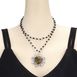 Close-up of double layer black beaded necklace with a sun pendant and vintage style stone center.