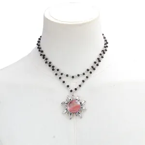 Detailed view of the double-layer black beaded necklace featuring a silver sun pendant.