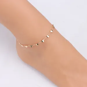 Gold-colored dainty anklet featuring multiple small heart charms, delicate close-up detail shot.