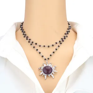 Close-up detail of the double-layer black beaded necklace featuring a purple sun pendant.