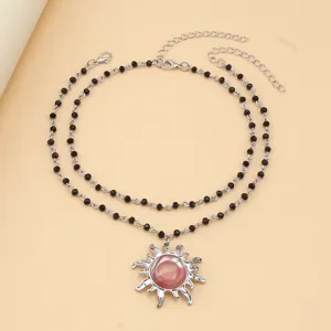 Double layer black beaded necklace with pink sun pendant, elegant fashion jewelry accessory detail.