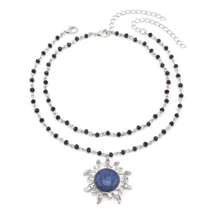 Detailed view of a double-layered black beaded necklace featuring a blue stone sun pendant.