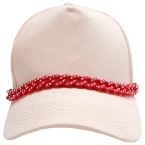 Detail of beige baseball cap featuring a bright red rhinestone Cuban chain accessory.